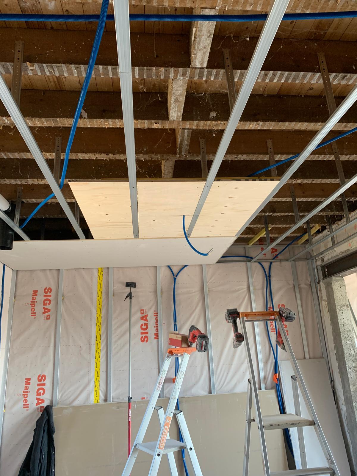 Isolation sous plancher bois avec ossature métallique, passage des réseaux électriques et pose de plaques support avant fermeture du plafond