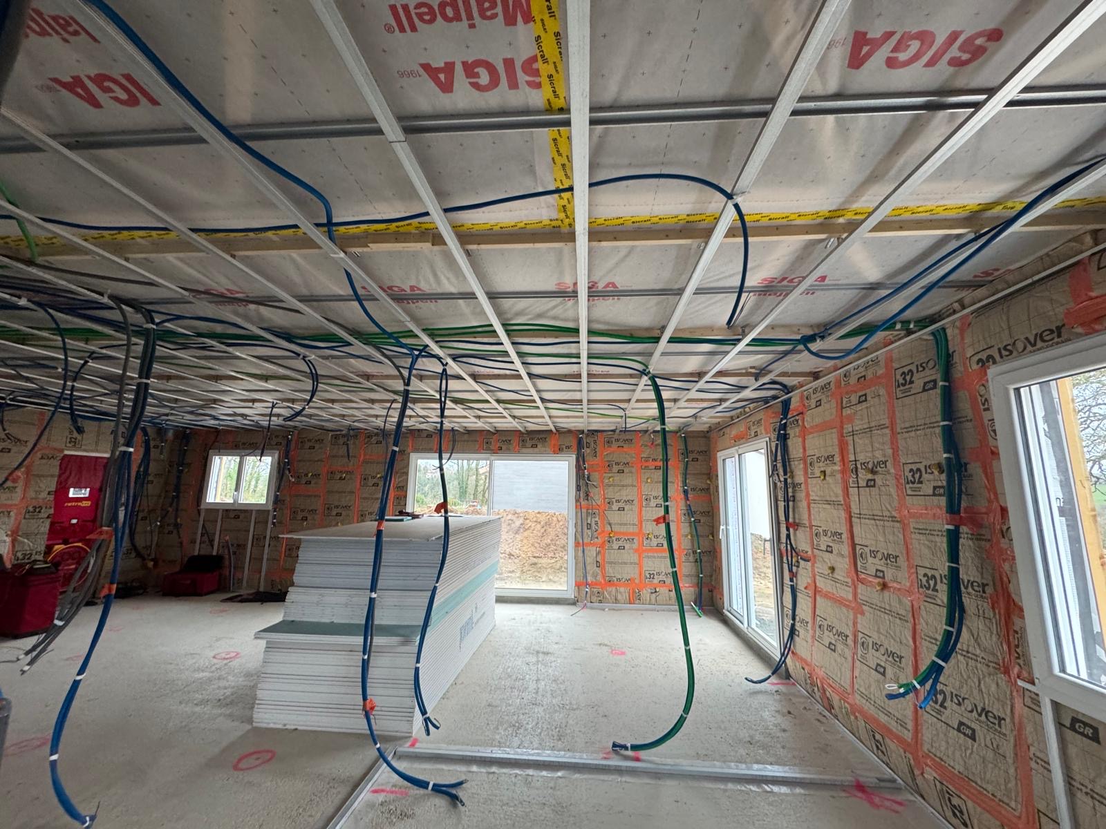 Chantier d’isolation intérieure et plâtrerie sèche avec pose de rails de plafond, isolant thermique et réseaux techniques avant installation des plaques de plâtre.