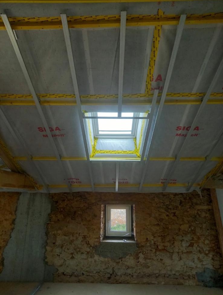 Doublage intérieur avec ossature métallique, isolation thermique et membrane d’étanchéité à l’air posée sur mur existant.