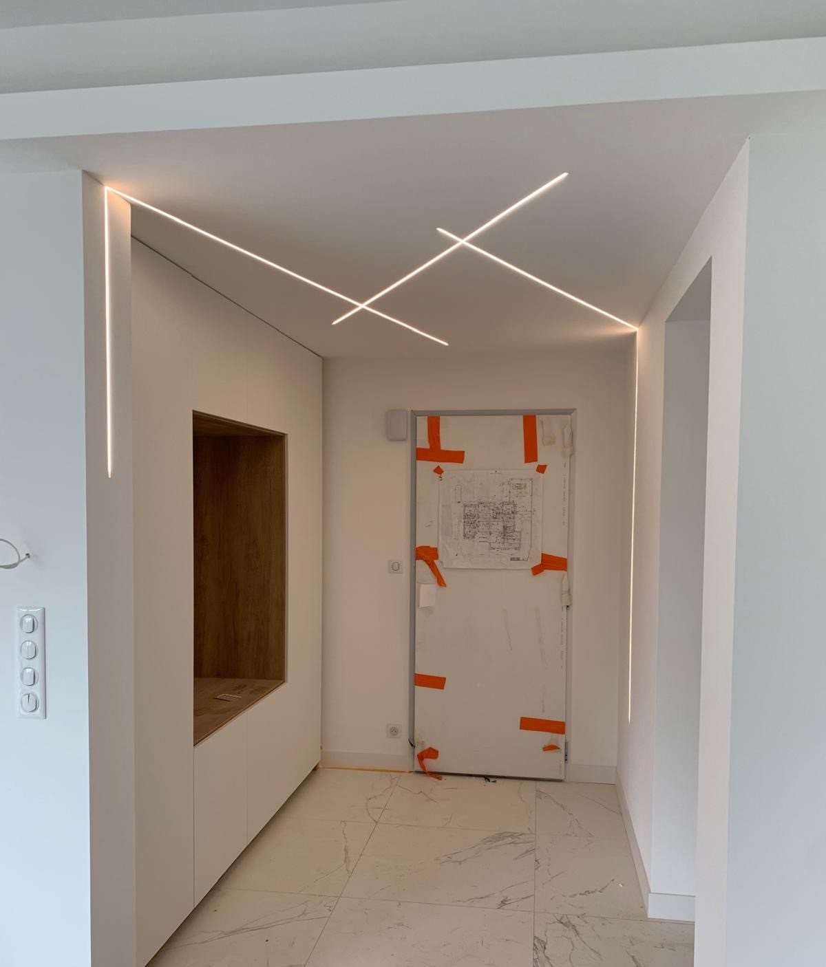 Couloir intérieur avec plafond en plaques de plâtre intégrant des lignes LED encastrées, finitions modernes et éclairage indirect