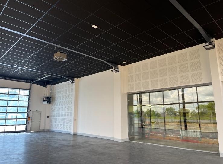 Grand espace professionnel avec plafond suspendu acoustique noir, murs en plaques de plâtre et larges baies vitrées
