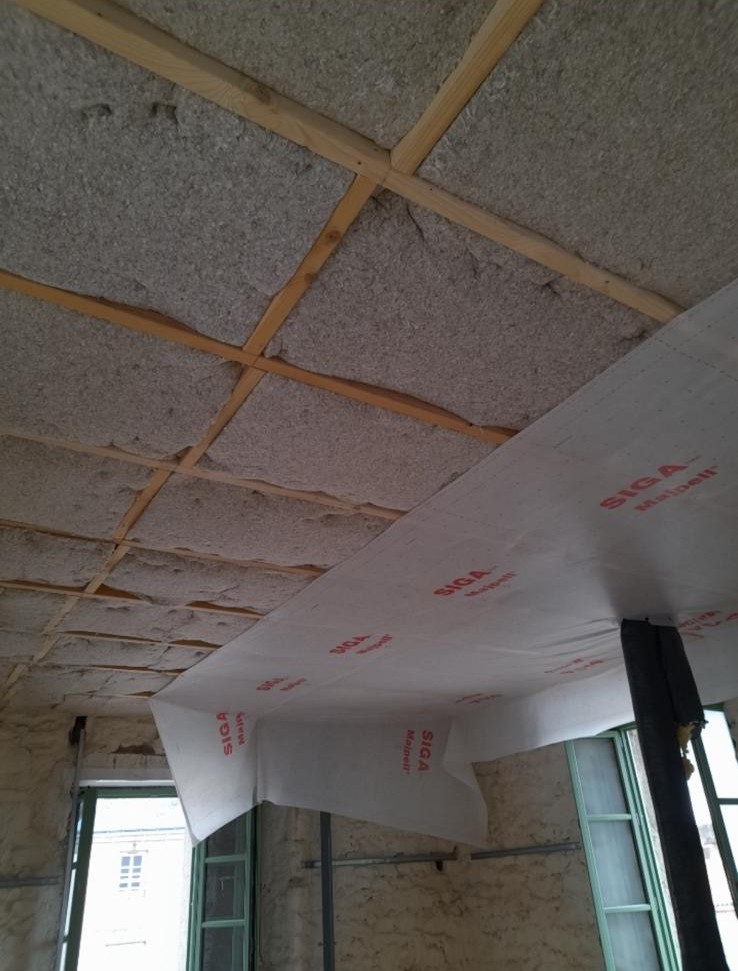 Isolation de plafond avec panneaux isolants entre tasseaux bois et membrane d’étanchéité à l’air posée en sous-face.